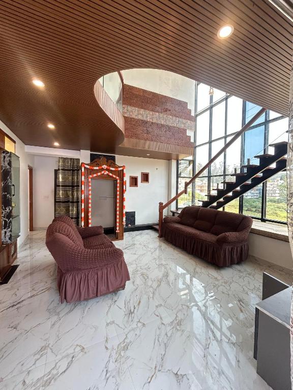 a living room with two couches and a staircase at Zarax home stay in Ooty