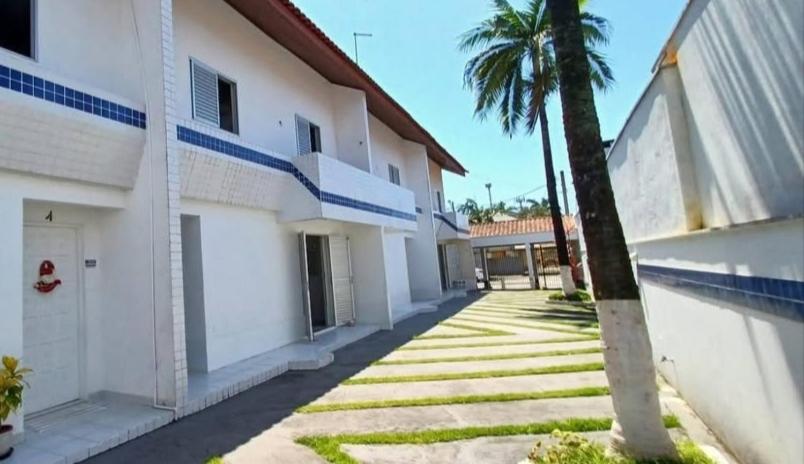 a building with a palm tree next to a sidewalk at Sobrado em Caiobá in Matinhos