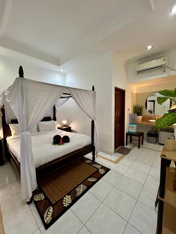 a bedroom with a bed with a canopy at Will and Ray's at Lori Beach Inn in Seminyak