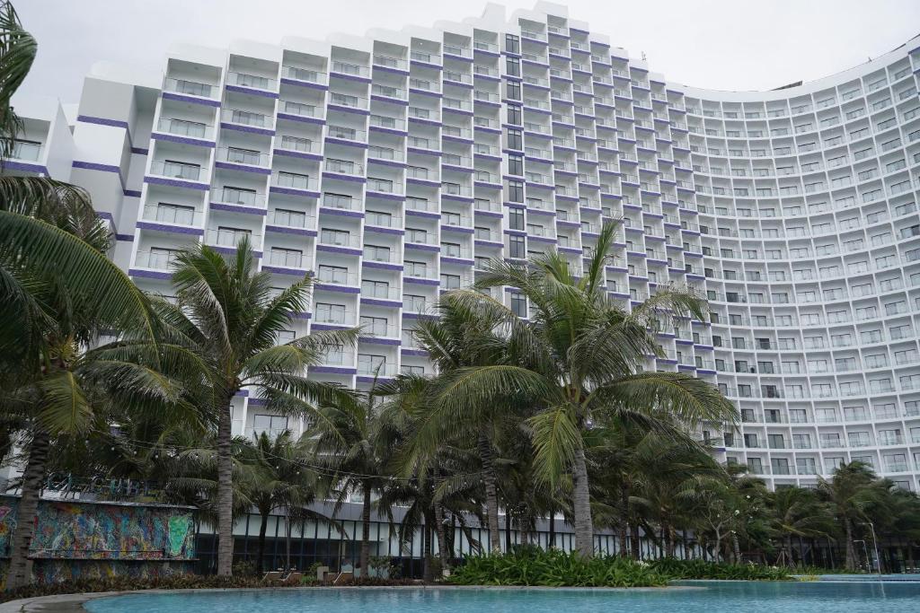 un grand bâtiment avec des palmiers devant dans l'établissement Havana Home at Arena Cam Ranh, à Cam Ranh International Airport