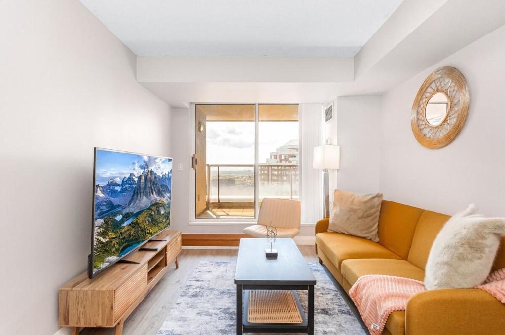Una sala de estar con un sofá y un televisor. en SkyView 2BR Plus Den Stunning Views Steps to SQ1 Mall, en Mississauga