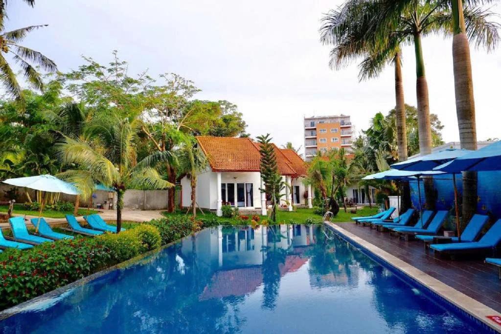 a swimming pool with blue lounge chairs and umbrellas at Terrace Resort in Phu Quoc