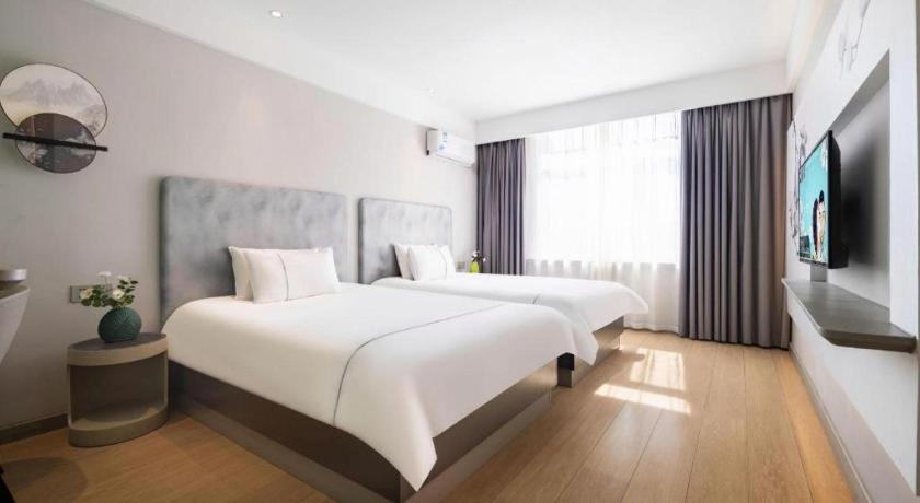a hotel room with two beds and a television at Magnotel Hotel Dandong Railway Yalv River in Dandong
