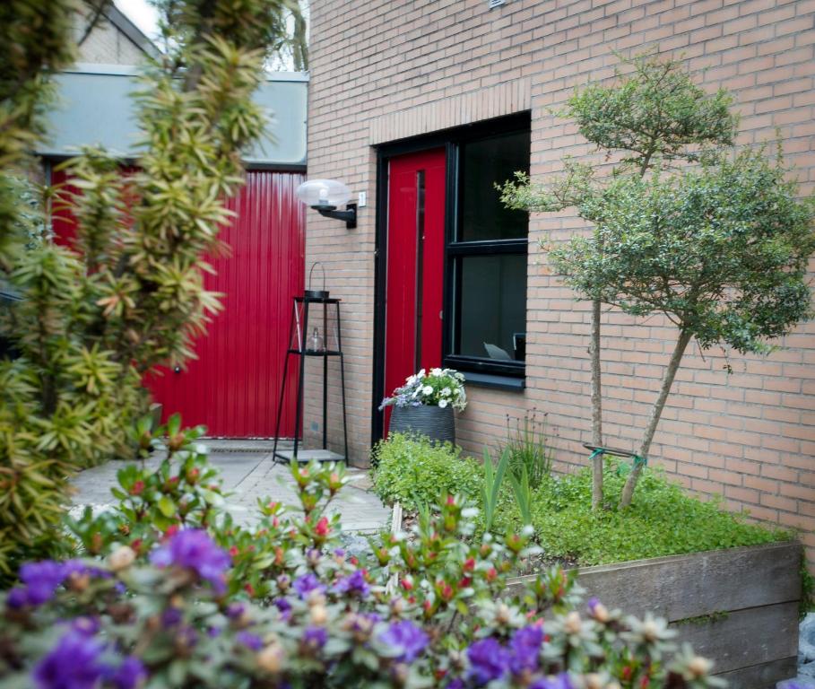 une porte rouge sur une maison en brique ornée de fleurs dans l'établissement Bed and Breakfast Holter, à Enschede