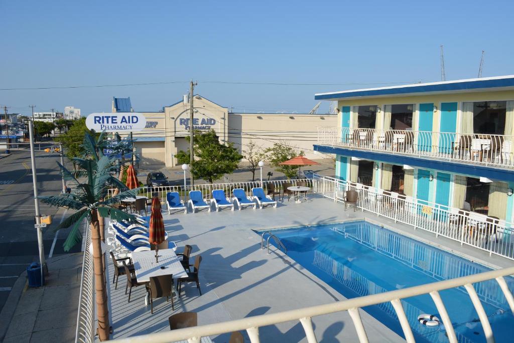 a view of a hotel swimming pool with chairs and a building at Royal Court Motel in Wildwood
