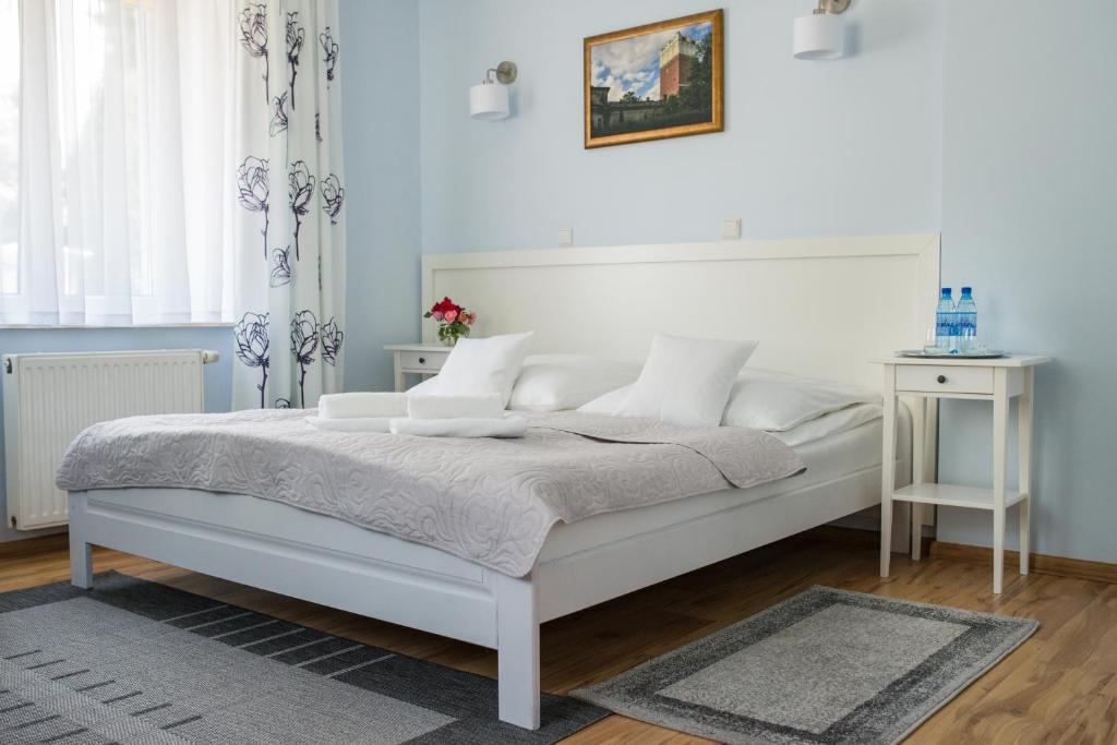 a white bedroom with a white bed and a table at Sandomiria in Sandomierz