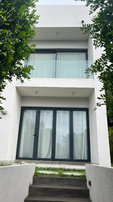 a white house with large windows and stairs in front at Azuri Mauritius - 3 Bedroom Townhouse in Roches Noires
