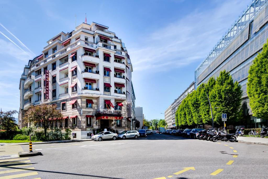 um edifício alto e branco com carros estacionados ao lado de uma rua em Hotel Eden em Genebra