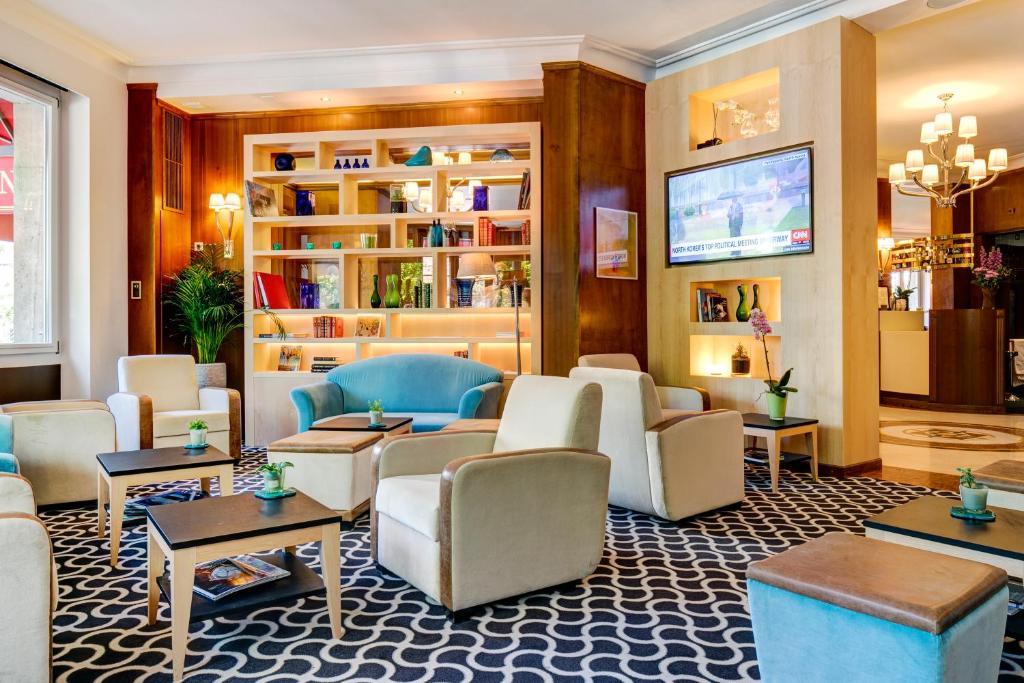 a lobby with couches and tables and a tv at Hotel Eden in Geneva