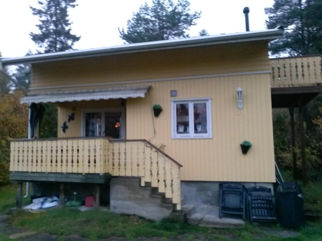 una pequeña casa amarilla con porche y escaleras en Holiday Home Sondre Hallangen, en Fagerstrand