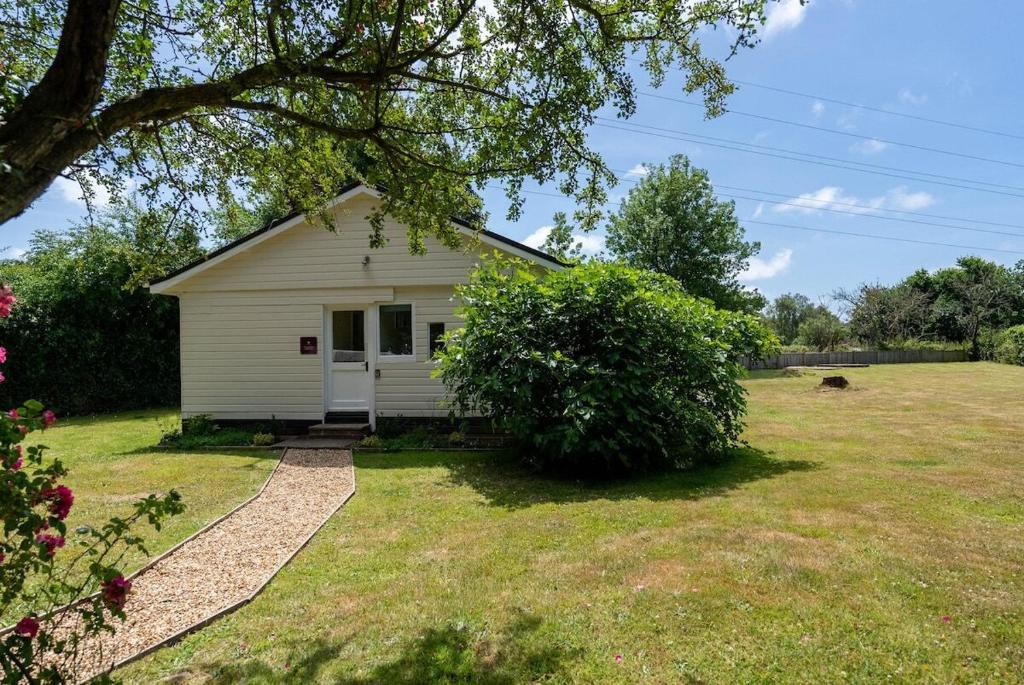 une petite maison blanche dans un champ d'herbe dans l'établissement Railway Carriages, à Hinton Admiral Station