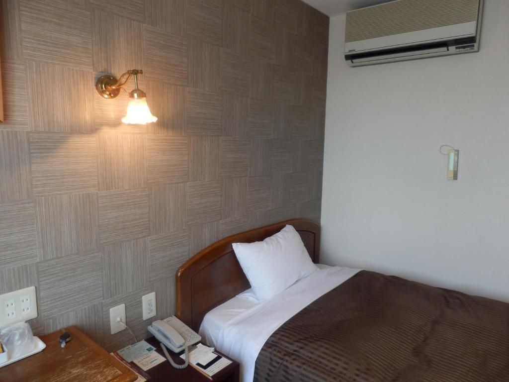 a bedroom with a bed with a lamp and a telephone at Famy Inn Makuhari in Chiba