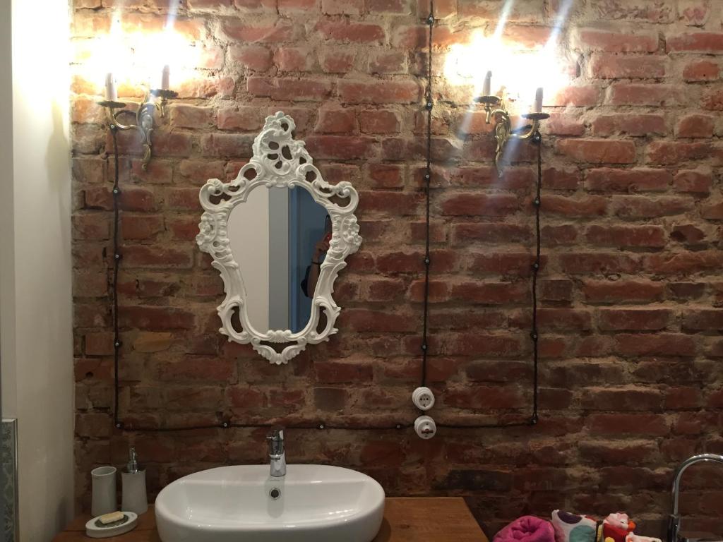 a bathroom with a white mirror on a brick wall at Sophisticated art deco near sea, centre and parks in Ventspils