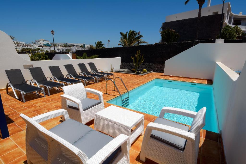 um pátio com cadeiras e uma piscina em Villa Oasis em Playa Blanca