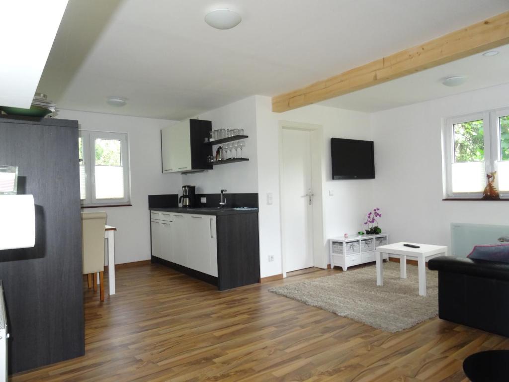 uma cozinha e sala de estar com paredes brancas e pisos de madeira em Schwedenhaus im Grünen em Oranienburg