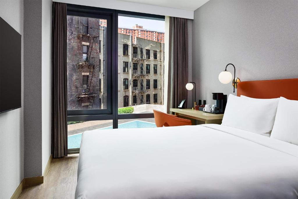 um quarto de hotel com uma cama e uma janela grande em The George At Columbia Harlem, Tapestry Collection By Hilton em Nova Iorque