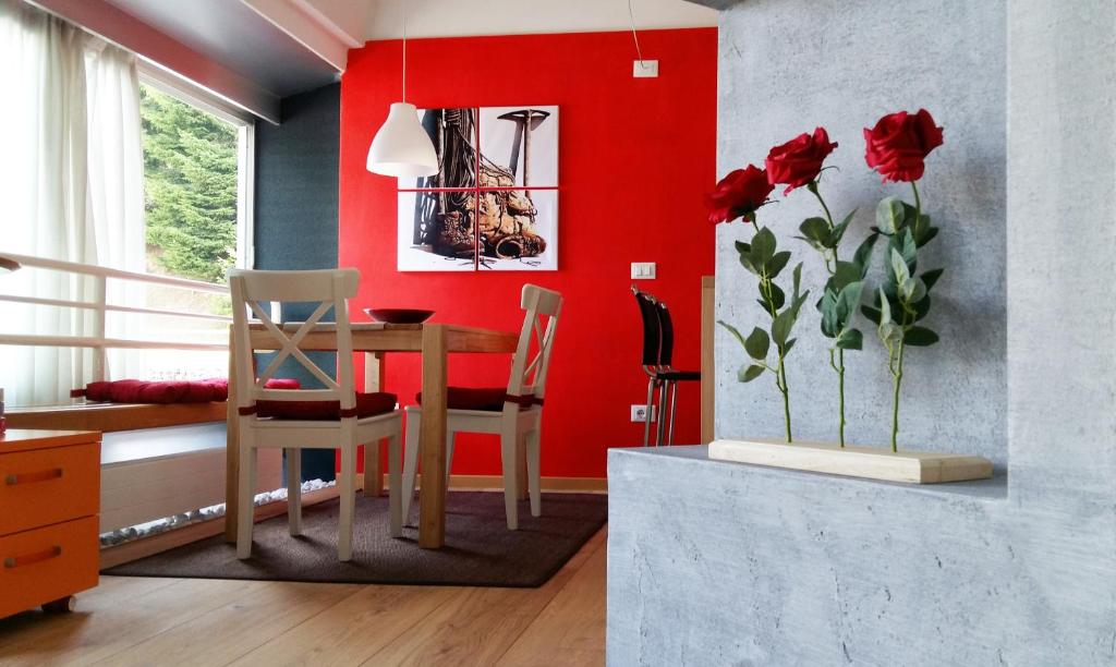 a dining room with red walls and a table and chairs at Nido nelle Dolomiti Apartment in Marilleva
