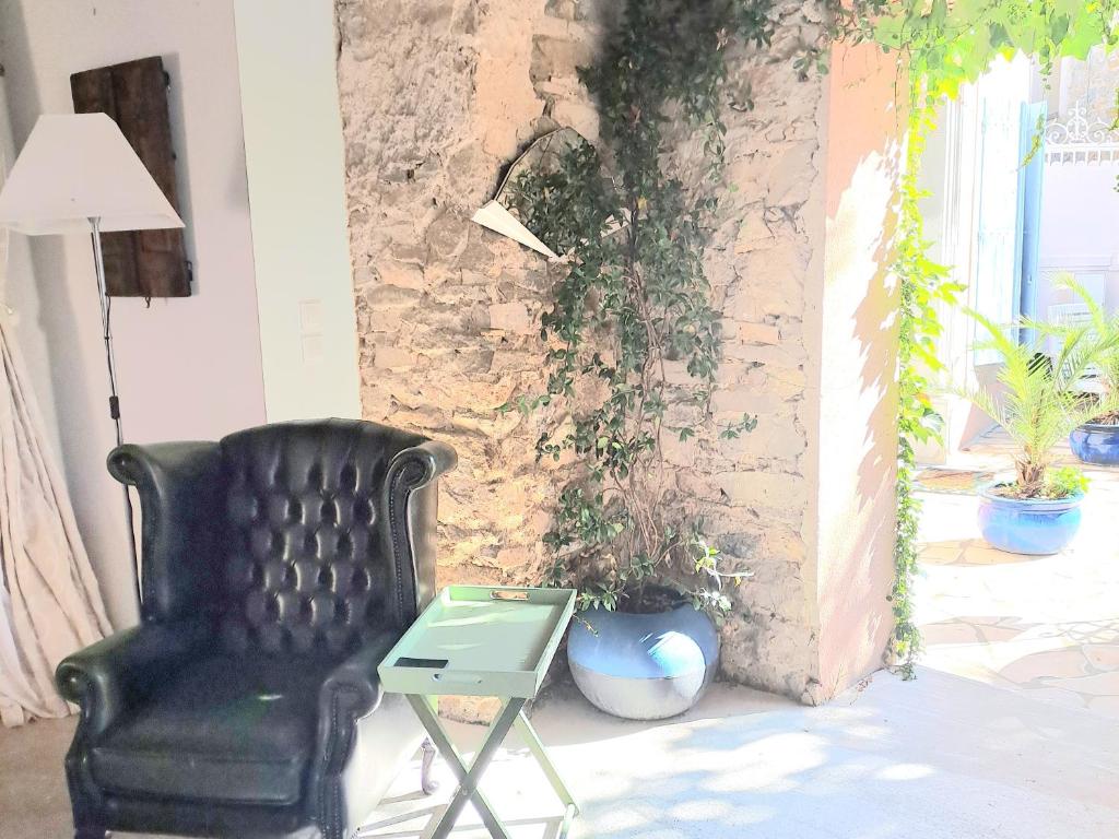 La maison SPA, PISCINE et CLIMATISATION في Sainte-Valière: كرسي أسود وطاولة بجانب جدار من الطوب