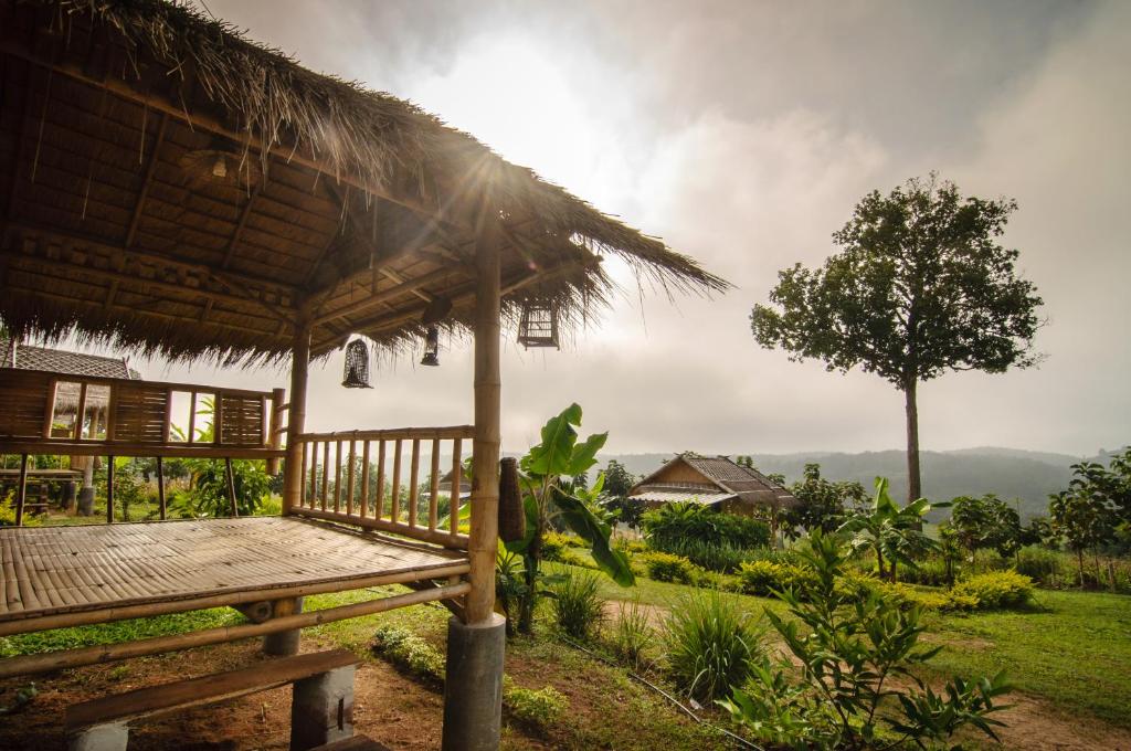 una cabaña con un banco y un árbol en un campo en Phoomtada Homestay, en Wiang Pa Pao
