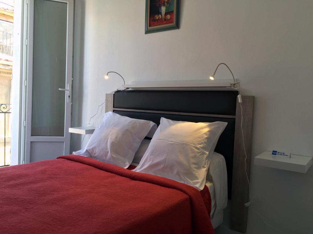 - un lit avec une couverture rouge et des oreillers blancs dans l'établissement Appartement Le Saint-Charles, à Marseille