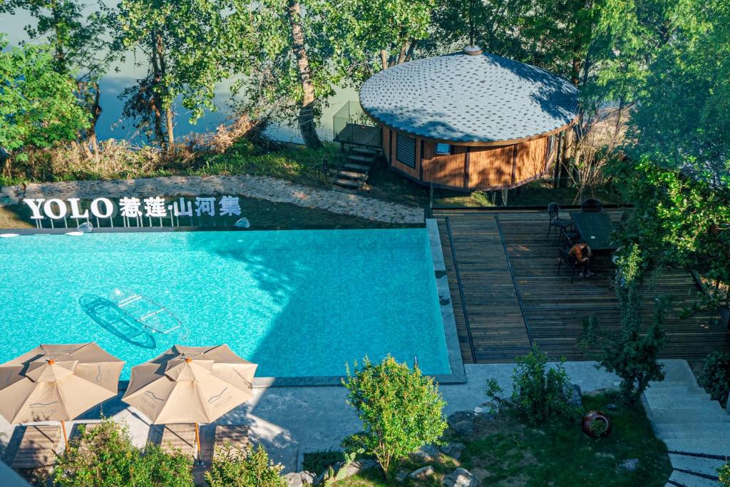 uma vista sobre uma piscina com guarda-sóis e uma casa em Zhangjiajie YOLO RELIAN Mt and River Collection-Riverside hotel with sunrise,sunset views, ticket service for attractions, afternoon tea,coffee, and laundry service em Zhangjiajie