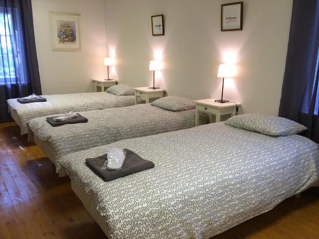 three beds in a room with two lamps on them at Kalda Guesthouse in Haapsalu