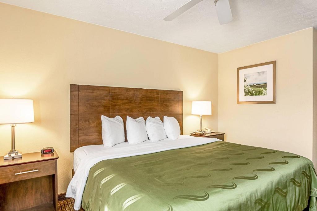 Una cama grande en una habitación de hotel con dos lámparas. en Quality Inn Burkeville Hwy 360 & 460, en Burkeville