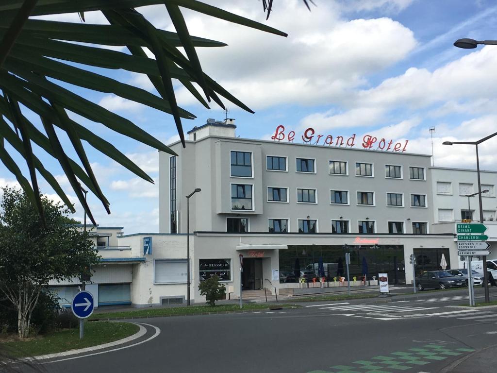 a large white building with a red sign on it at Le Grand Hotel in Maubeuge