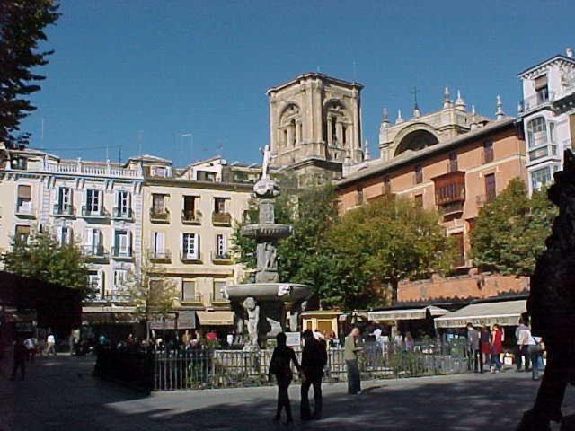 a group of people walking around a fountain in a city at Casa Palacio López Daza in Granada