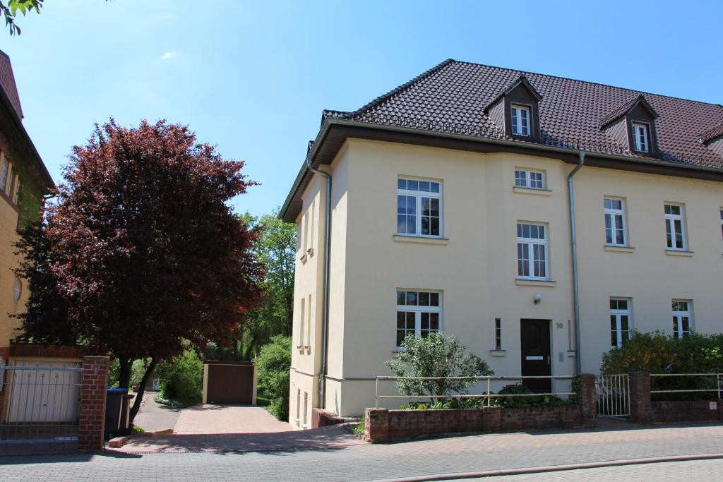 a white house with a black roof on a street at Ferienwohnung Brück in Bitterfeld