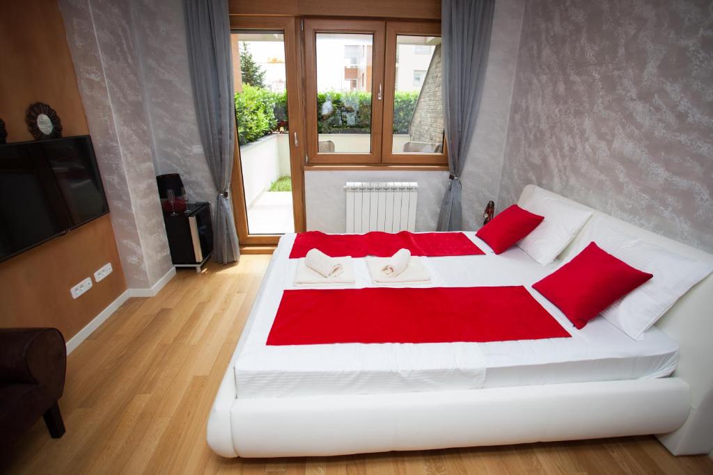 una camera da letto con un letto bianco con cuscini rossi di Gentleman Dog Apartment a Belgrado