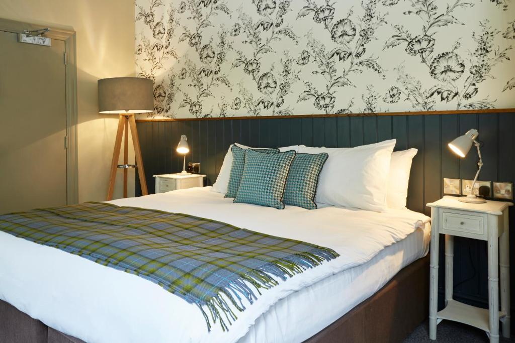 a bedroom with a bed with a green and white blanket at Dartbridge Inn by Greene King Inns in Buckfastleigh