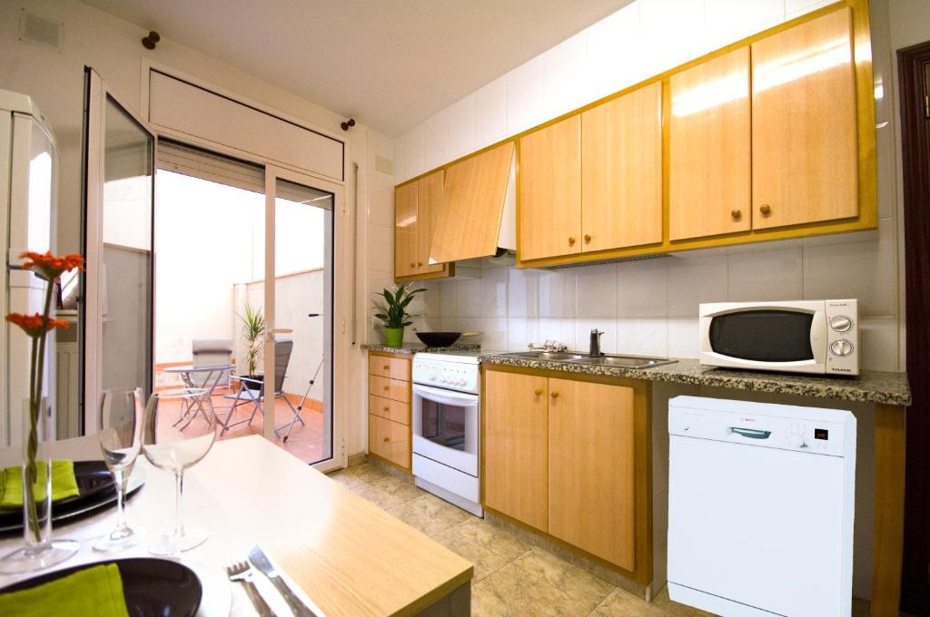 een keuken met houten kasten en een witte magnetron bij Apartments Figueres in Figueres