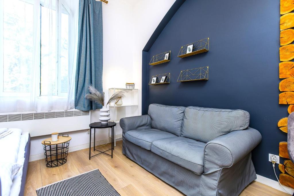 a living room with a couch and a blue wall at Rently Apartments in Old Town in Kraków