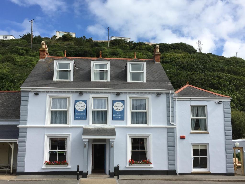 een wit huis met een heuvel op de achtergrond bij Portreath Arms in Portreath