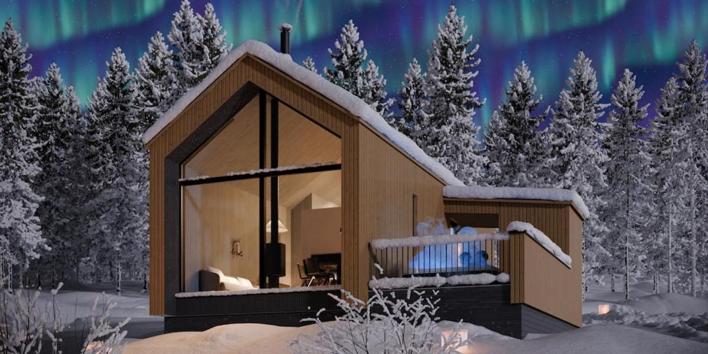 a cabin in the snow with the northern lights in the sky at North Suite Nova by Hilla Villas in Kittilä