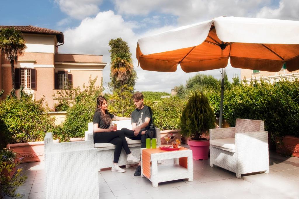 due persone sedute su una panchina sotto un ombrello di Best Western Ars Hotel a Roma