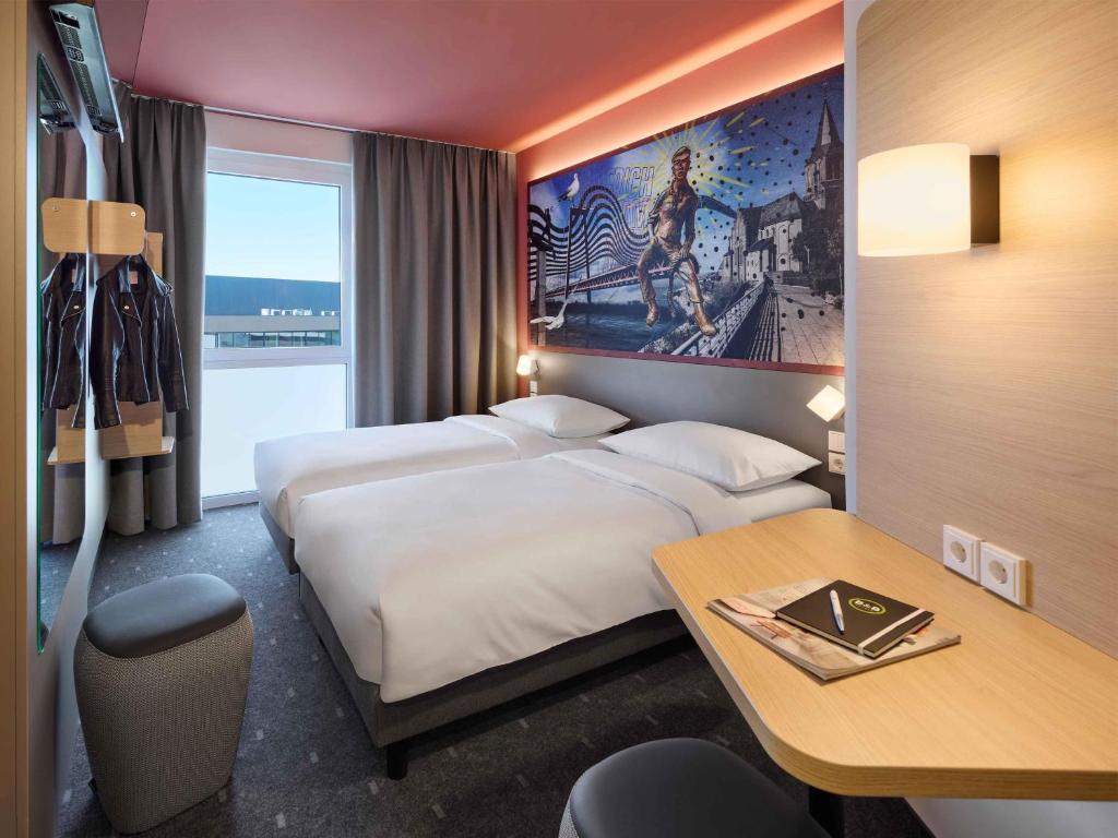 a hotel room with two beds and a desk at B&B HOTEL Emmerich in Emmerich