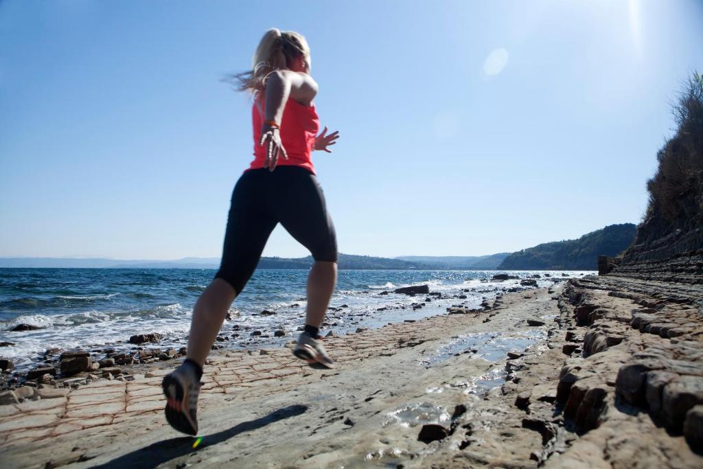 a woman jumping in the air on the beach at Hotel Neptun - Terme & Wellness Lifeclass in Portorož