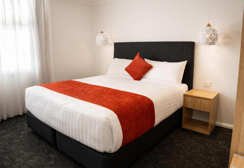 a bedroom with a large bed with a red blanket at Econo Lodge Mildura in Mildura