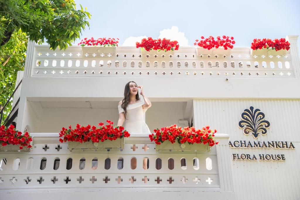 a woman standing on a balcony talking on a cell phone at Rachamankha Flora House in Chiang Mai