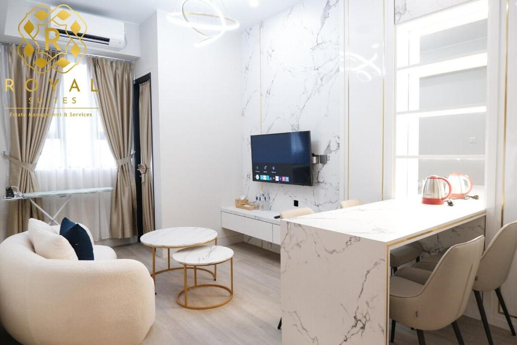 ナゴヤにあるRoyal Suites 2BR - Baloi Apartmentのカウンターと椅子のある白いリビングルーム
