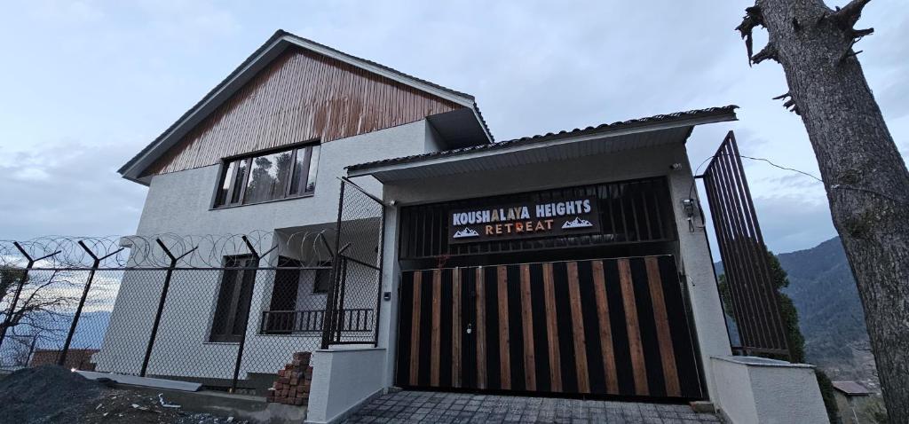 a building with a garage with a sign on it at Koushalaya Heights Retreat in Batoti