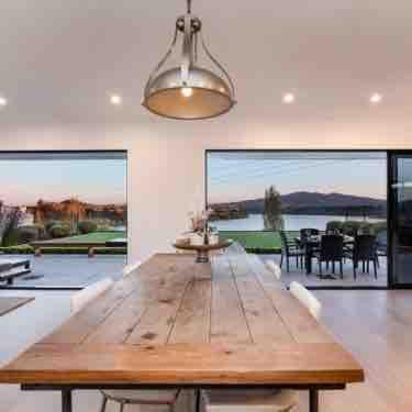 a dining room with a wooden table and a large window at Karapiro Lakeside in Karapiro