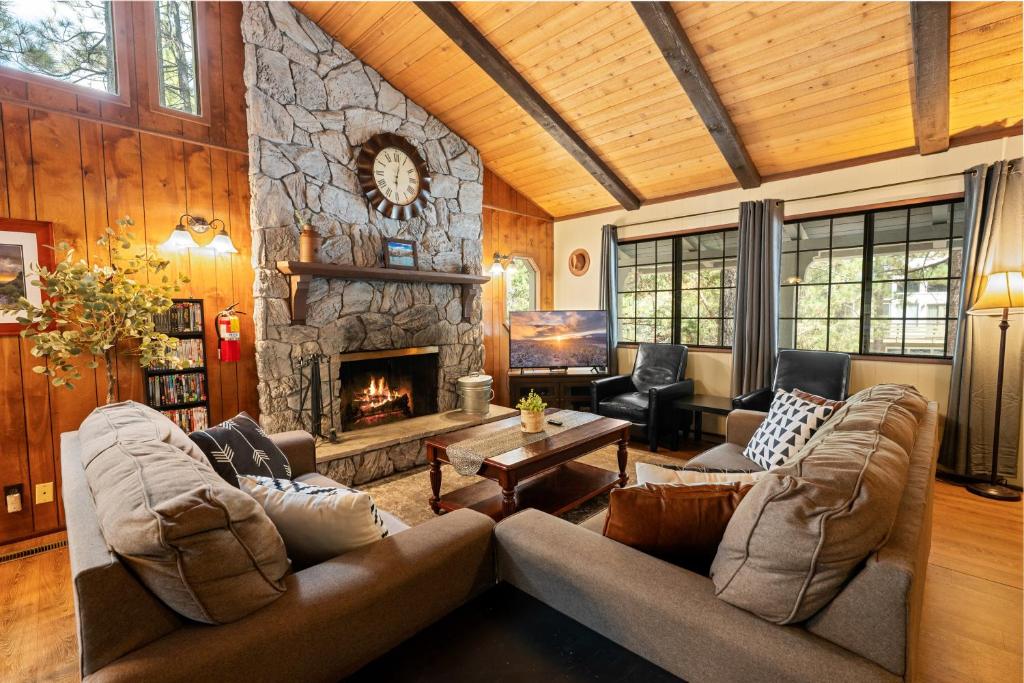 a living room with couches and a stone fireplace at Bear Woods 3BR Retreat in Big Bear City