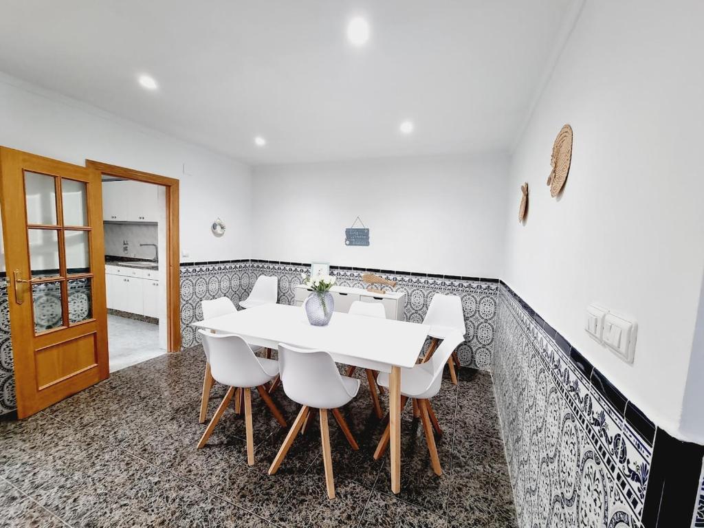 Un comedor con una mesa blanca y sillas blancas. en La Maison du Port, en Puerto Sagunto