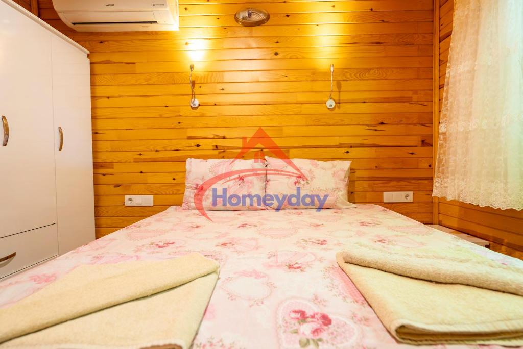 Un dormitorio con una cama con colcha floral y paredes de madera. en Cirali Camping, en Kemer
