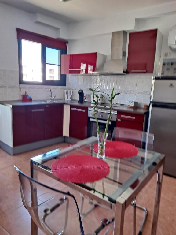 a kitchen with a glass table with two red chairs at Margarita House in Arrecife