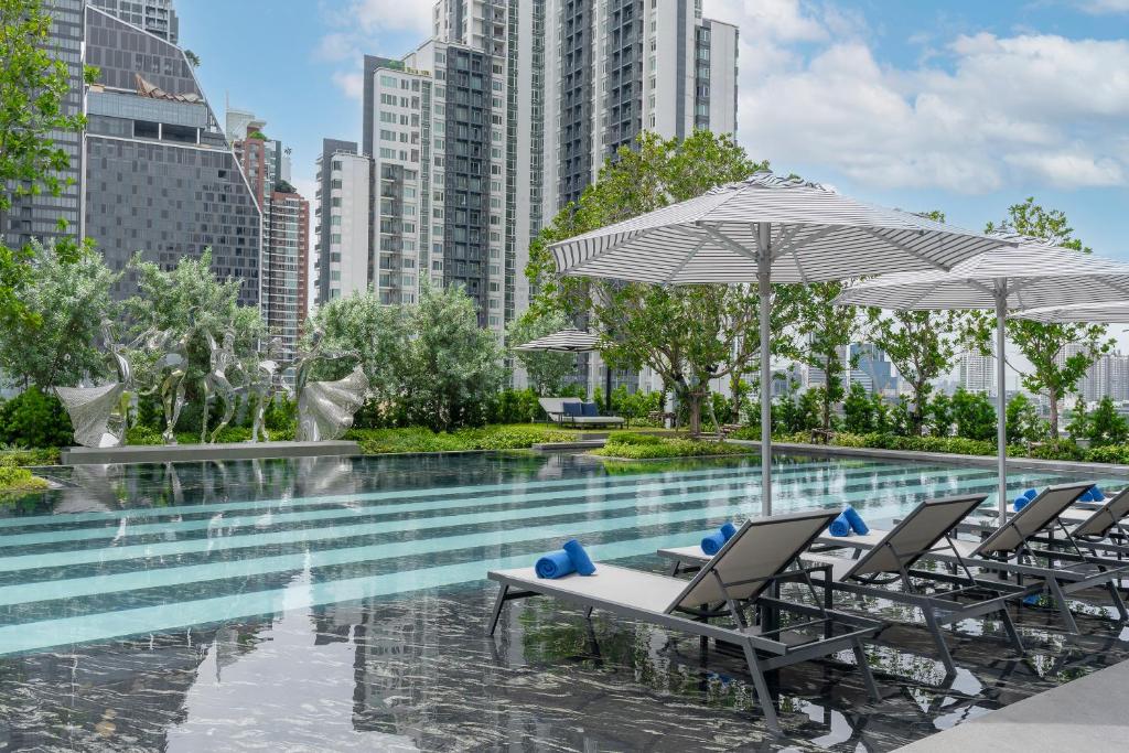 a pool with chairs and umbrellas in a city at La Clef Bangkok by The Crest Collection in Bangkok