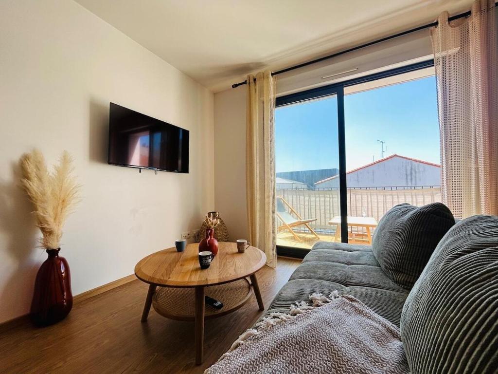 een woonkamer met een bank, een tafel en een raam bij Casa Arcade Rougé - Premium - Terrasse - Parking in Cholet